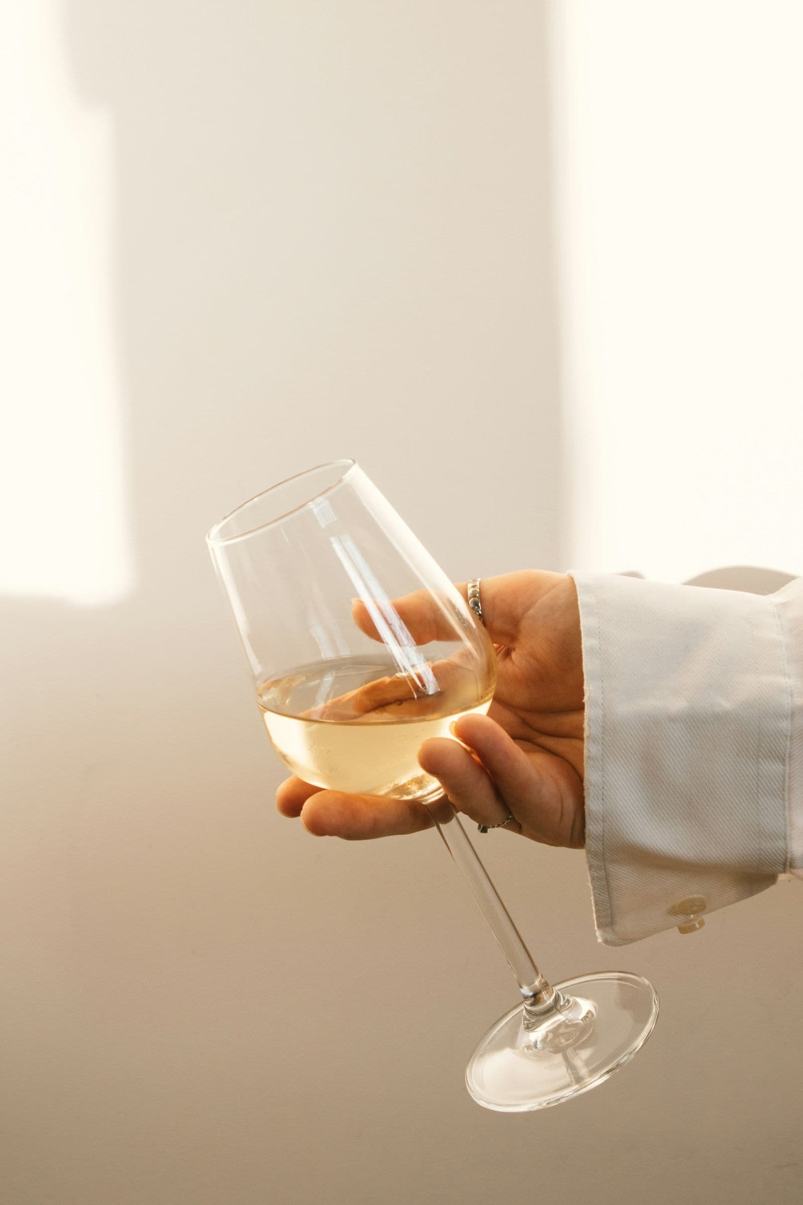 Hand hält ein Glas mit hellem Weißwein