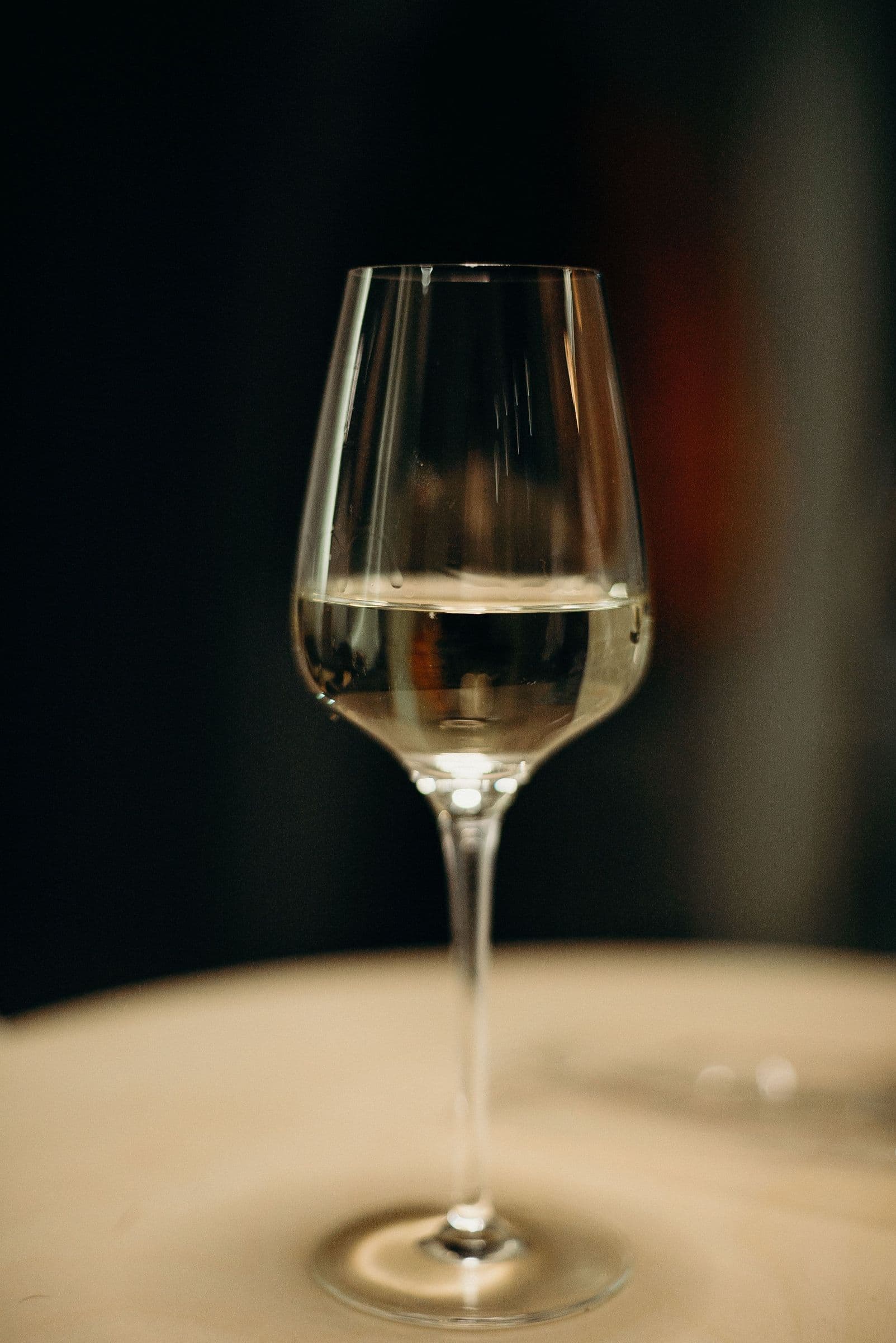 Glas Weißwein vor warmem, dunklem Hintergrund