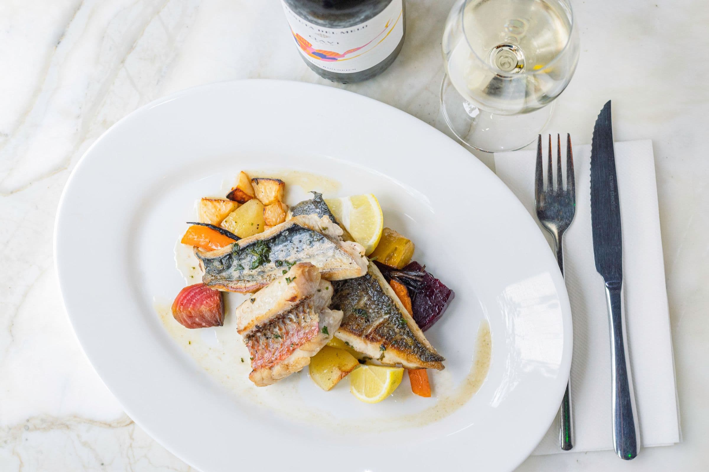Fischgericht mit einem Glas Weißwein auf einem Marmortisch
